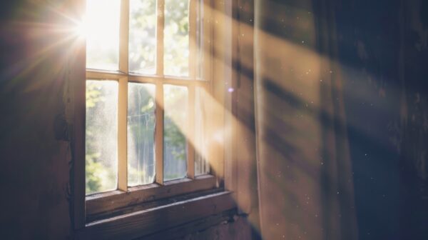 the sun shining through a window in a dark room